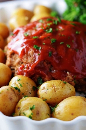 A closeup of this instant pot meatloaf with a tomato glaze and baby potatoes
