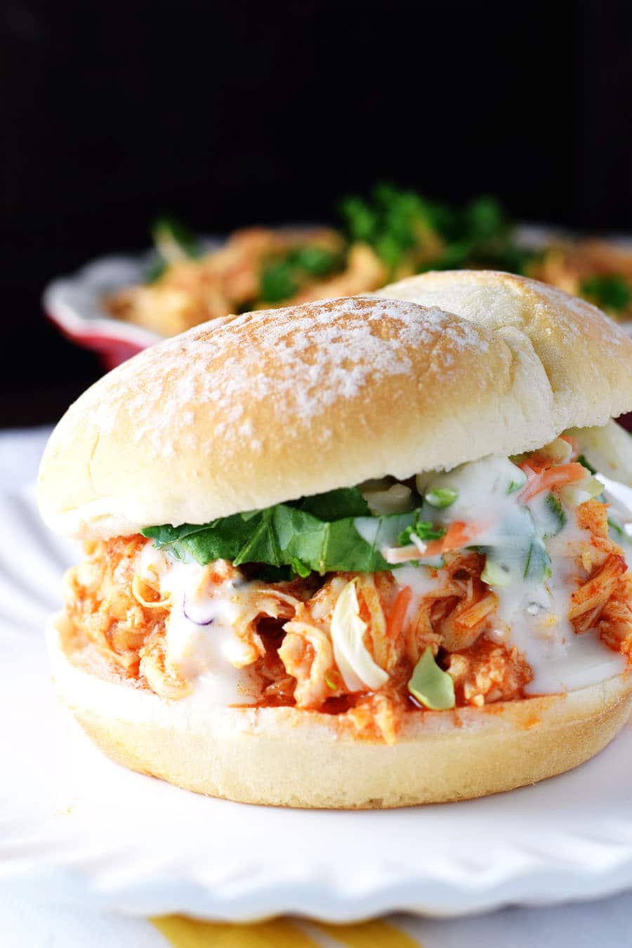 A closeup of this slow cooker buffalo chicken served as a sandwich
