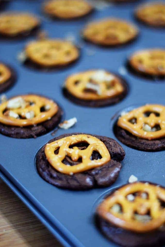 a mini muffin tin filled with these touchdown turtle bites topped with pretzel squares