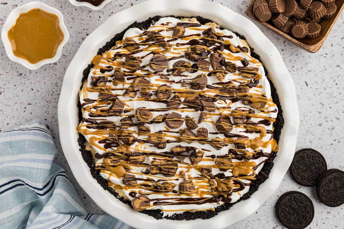 Peanut butter cup pie topped with chopped mini Reese's cups and drizzled with melted peanut butter and hot fudge.