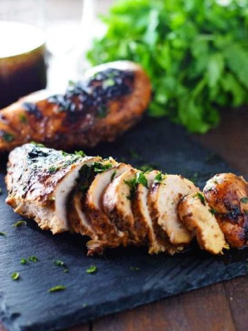 Best Chicken Marinade - Grilled Chicken on a black tray with parsley.