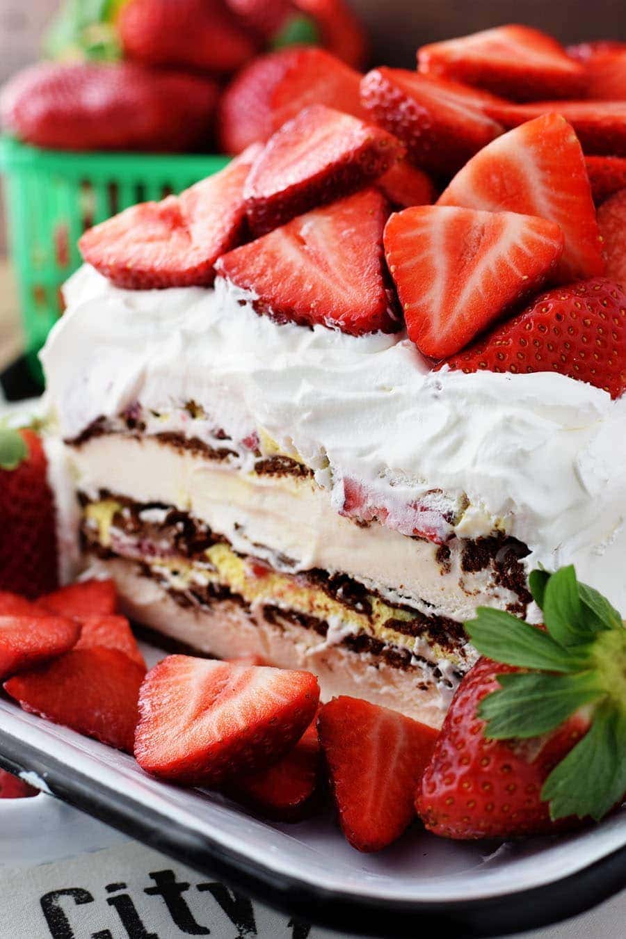 A close up of the midsection of this strawberry ice cream cake iced in whipped cream and topped with fresh strawberries