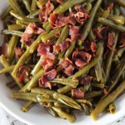 a white serving plate filled with these southern style green beans with crispy crumbled bacon