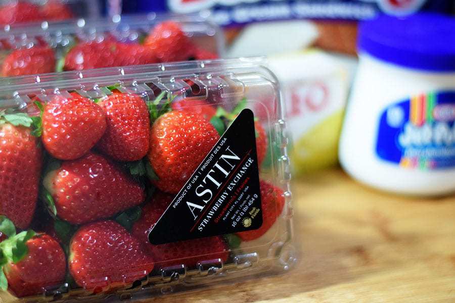 a closeup of a plastic carton of red strawberries to be used in strawberry ice cream cake