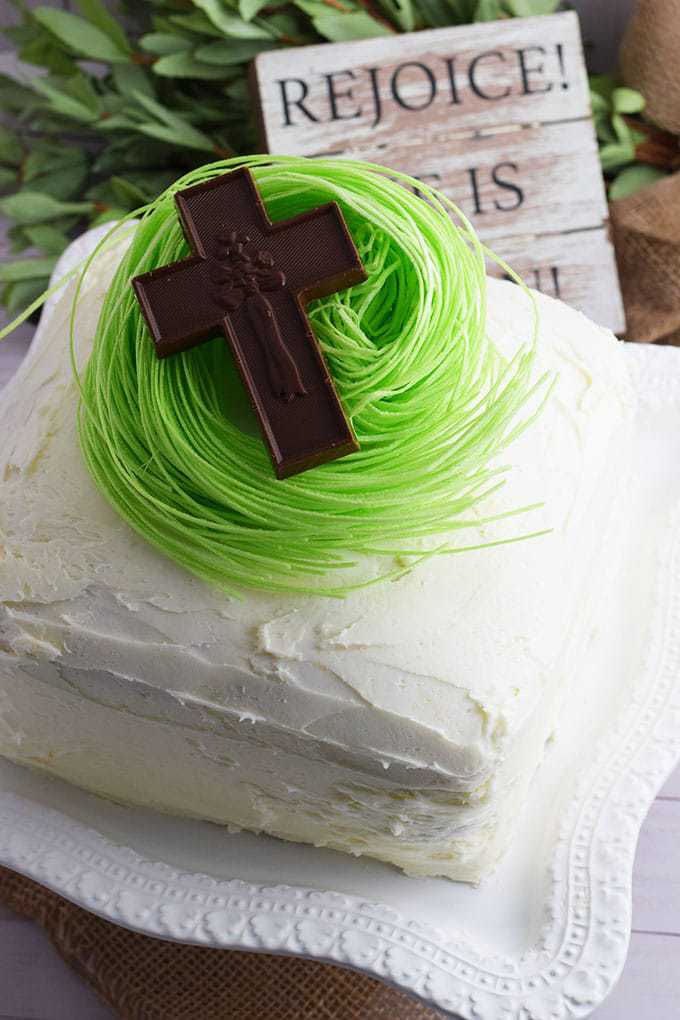 Almond Strawberry Layer Cake topped with edible green grass and a chocolate cross