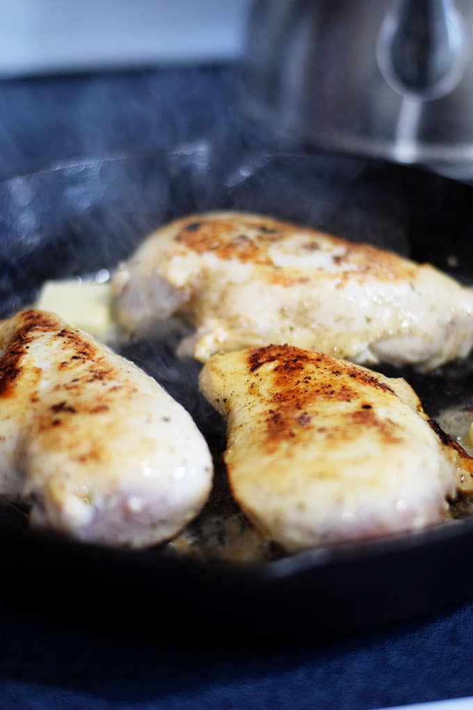 a close up of these lemon pepper chicken breasts cooking in a black cast iron skillet