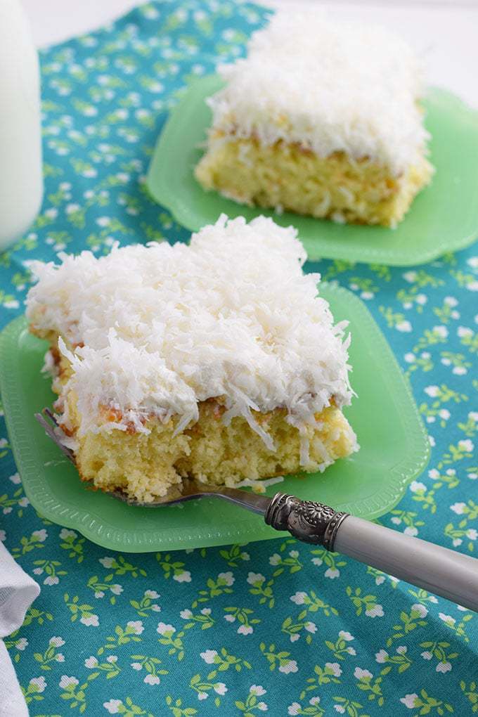 Slice of Easy Coconut Cream Poke Cake on a green plate with a fork