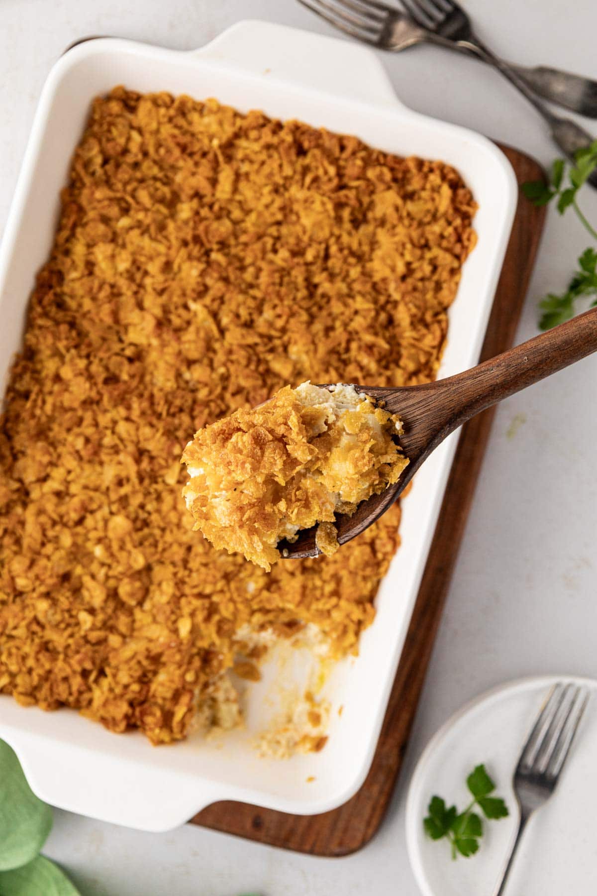 A wooden spoon, removing a scoop of potato casserole.