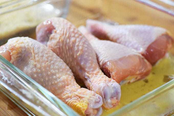 Chicken Drumsticks in Egg wash in clear dish.