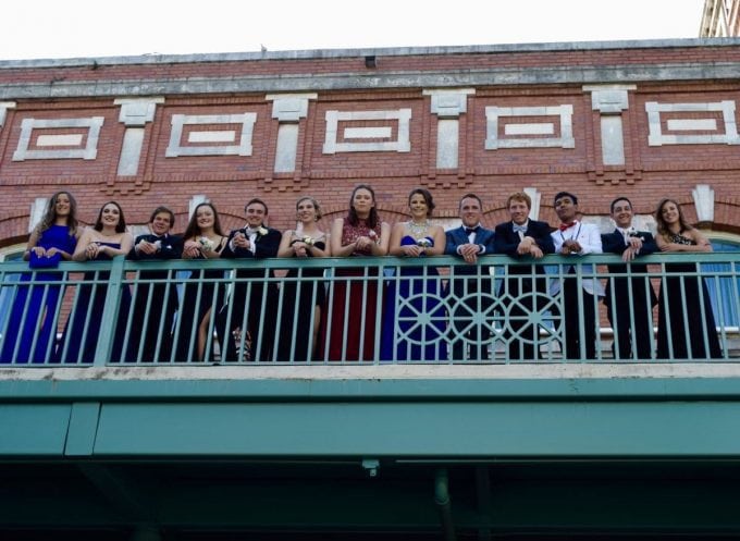 A group of people standing on the balcony of a brick building