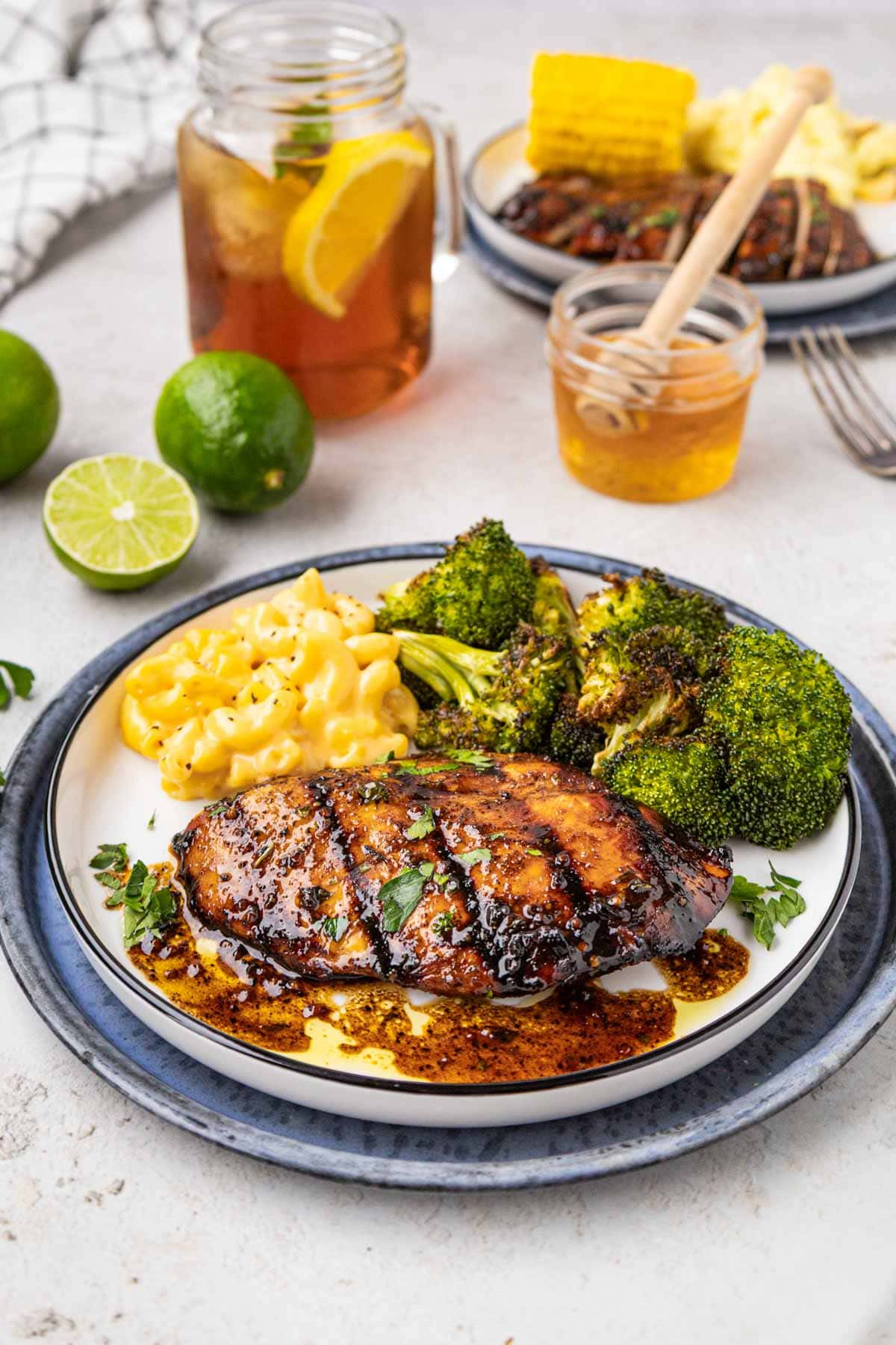 A grilled chicken breast on a plate with broccoli and mac and cheese.