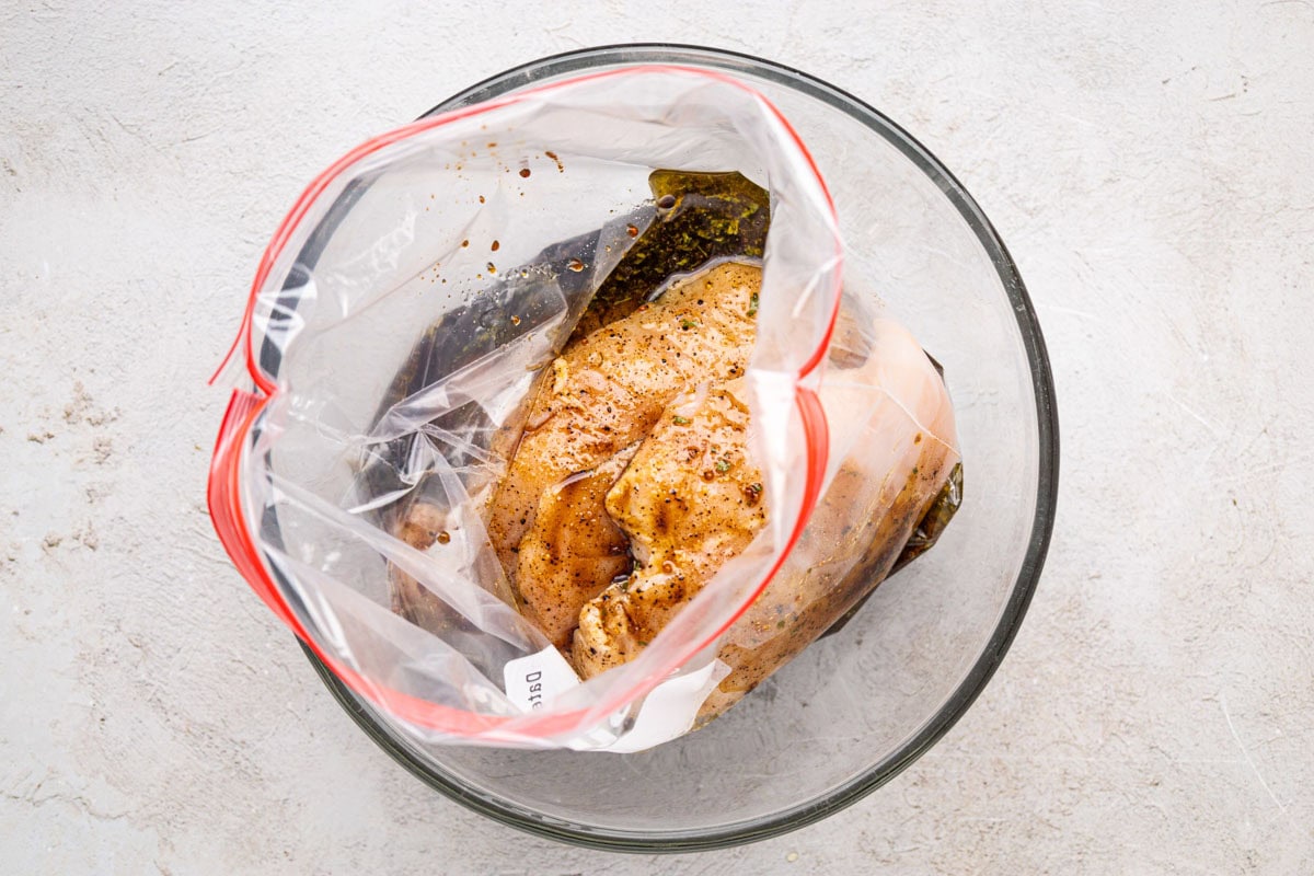 Chicken marinade poured over chicken breasts in a ziplock bag.
