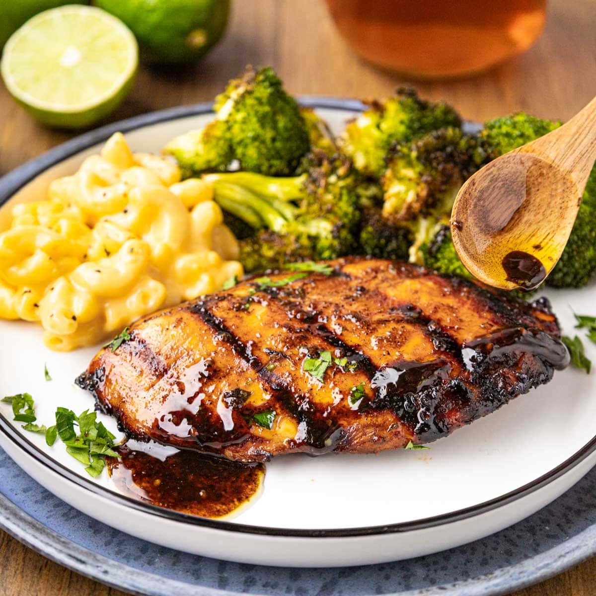 A marinated grilled chicken breast on a plate with broccoli and mac and cheese.
