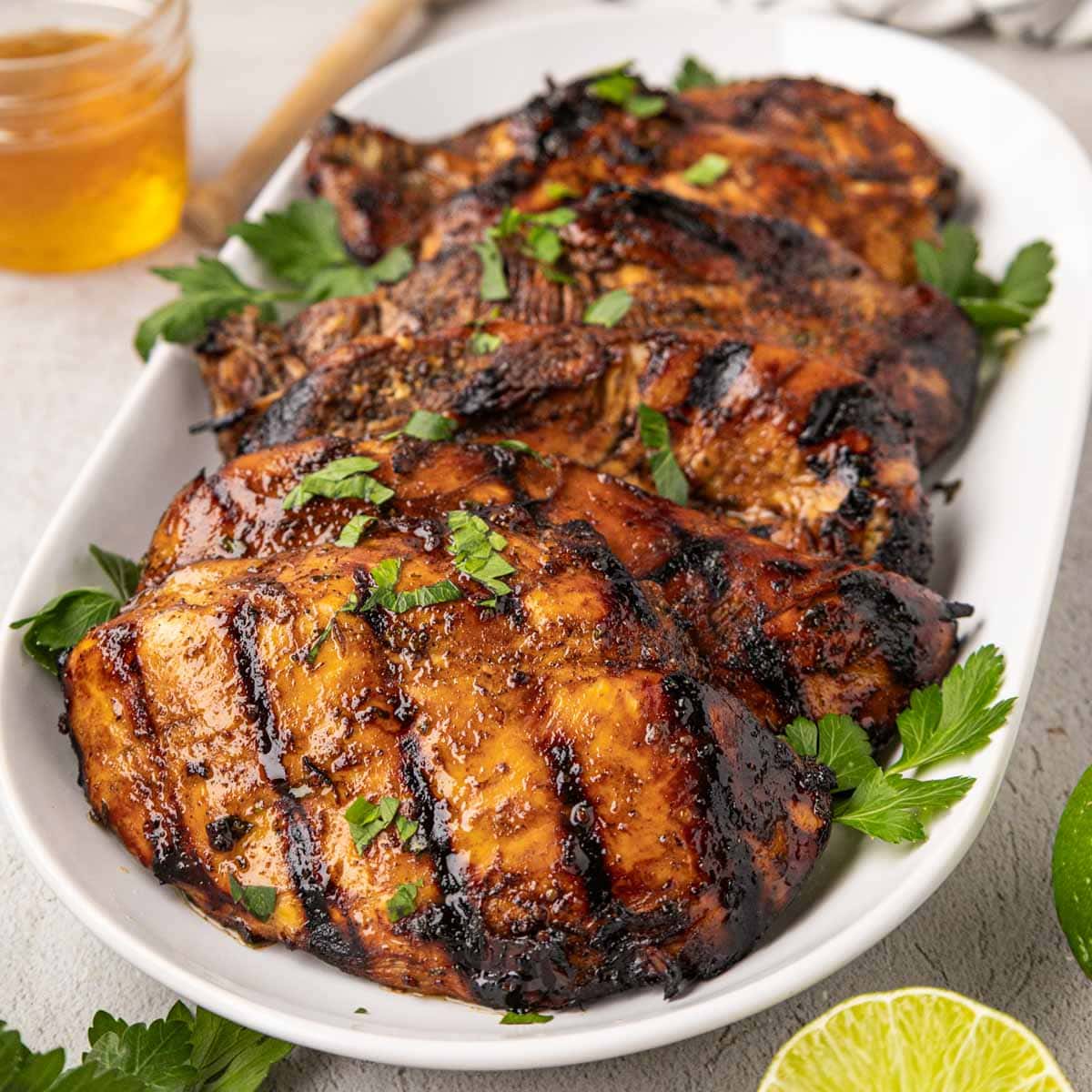 Chicken grilled in the best grilled chicken marinade on a white serving plate.