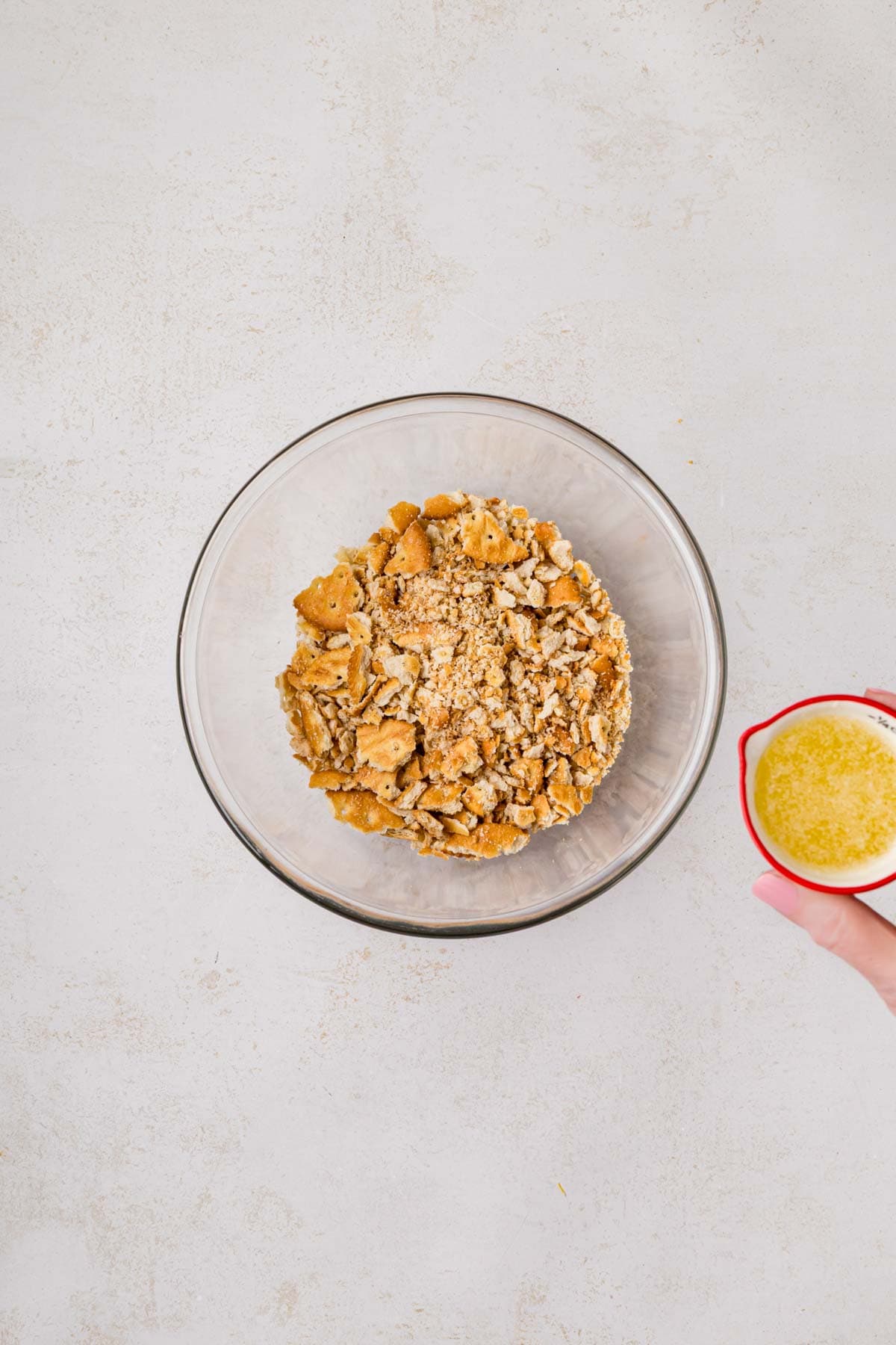 Pouring melted butter into crushed crackers.