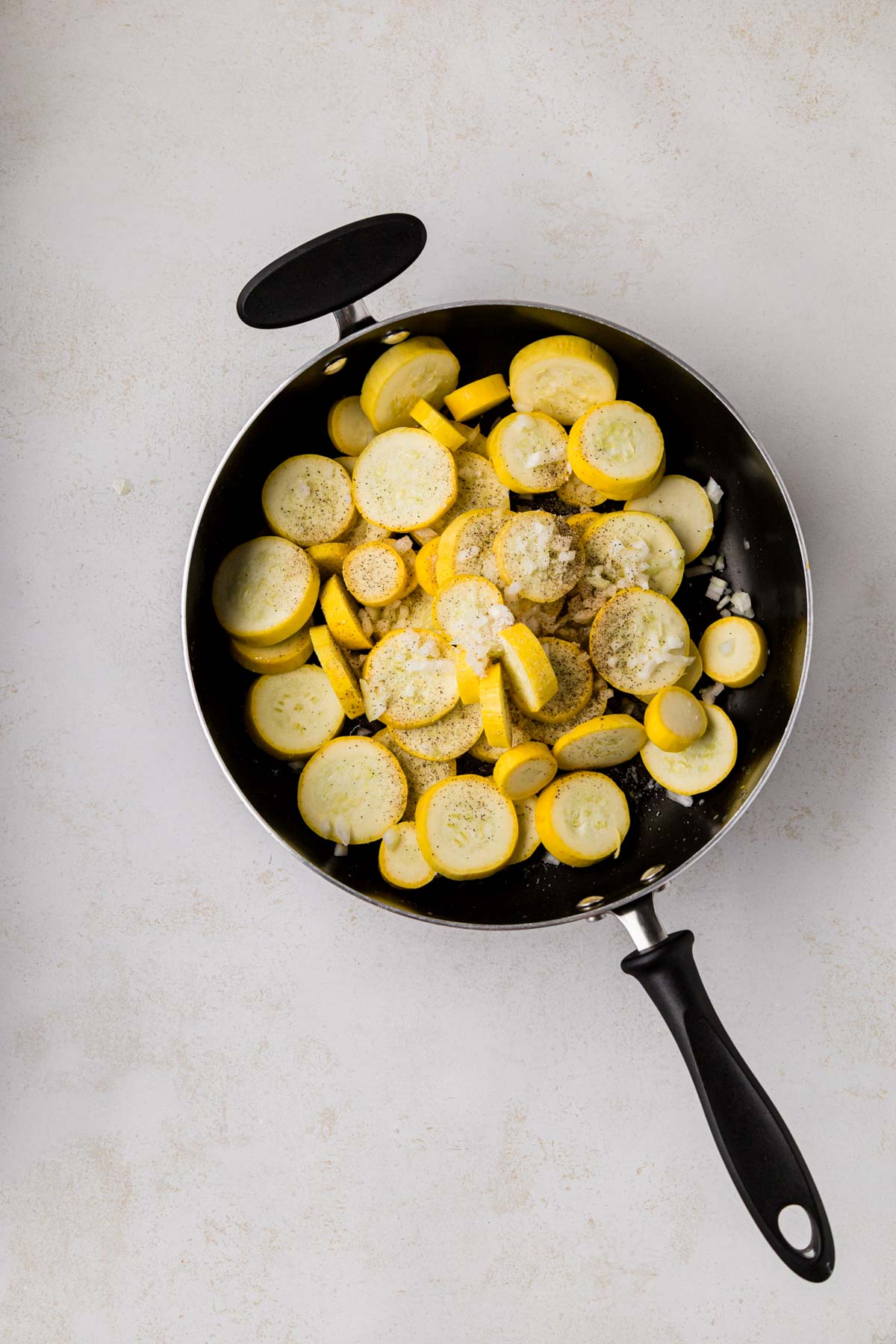 Squash and onion sautéing in a pan with seasonings.