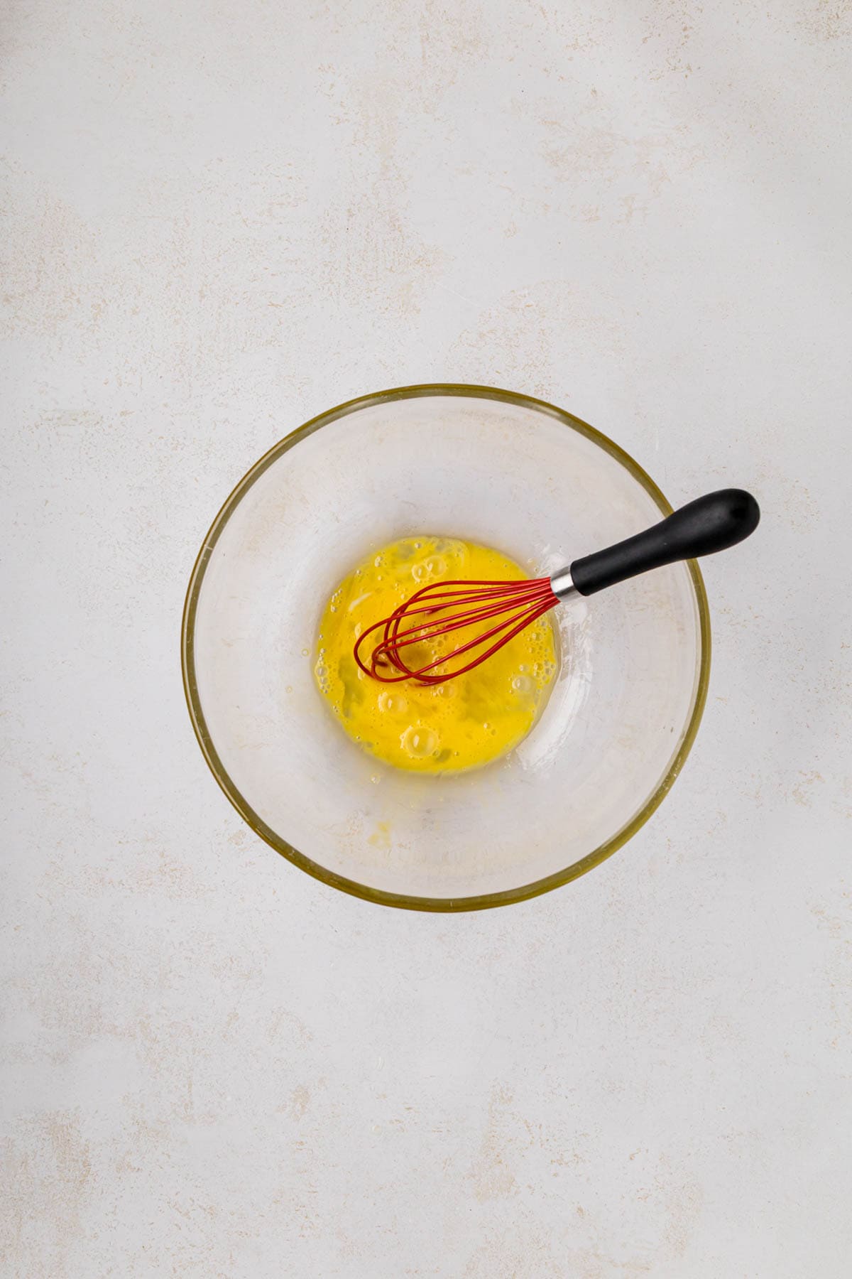 Eggs beaten together in a bowl with a wisk.