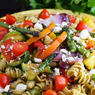 an overhead shot of this colorful grilled summer vegetable pasta salad recipe with crumbled cheese, rotini noodles, and chopped veggies