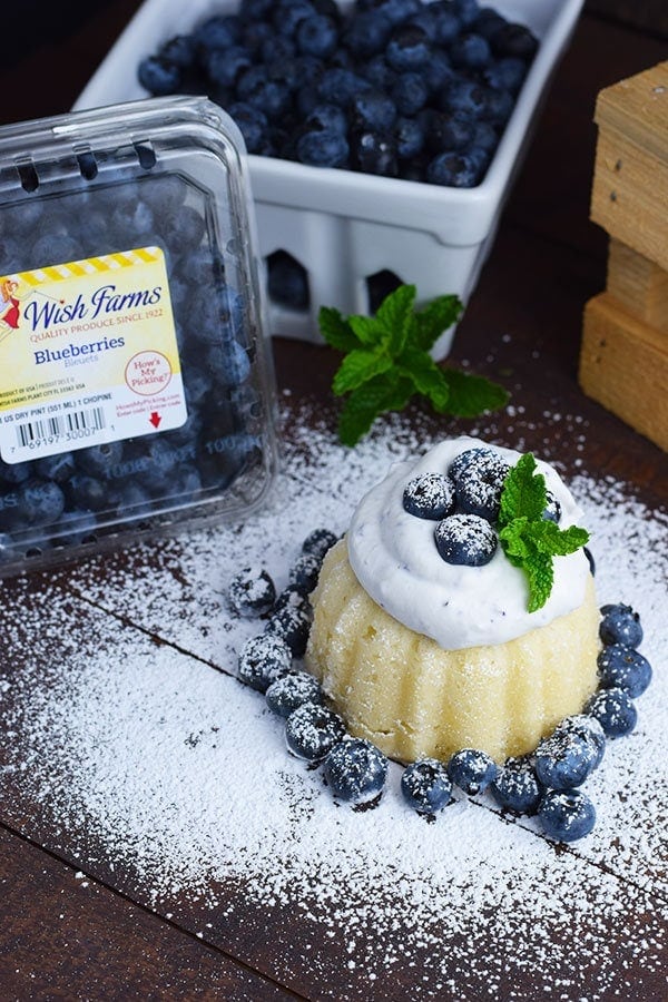 a mini almond bundt cake with fresh blueberry whipped cream, powdered sugar, mint leaves, and fresh blueberries