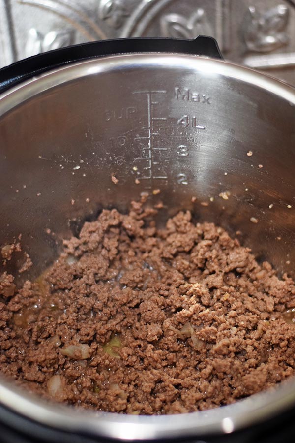 A close up of ground beef being browned in an instant pot insert to use in this easy goulash recipe