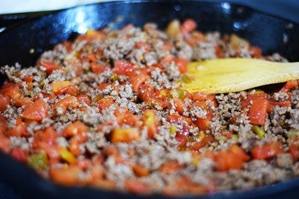 a close up of the ground beef with taco seasoning and chopped tomatoes for this taco spaghetti bake recipe