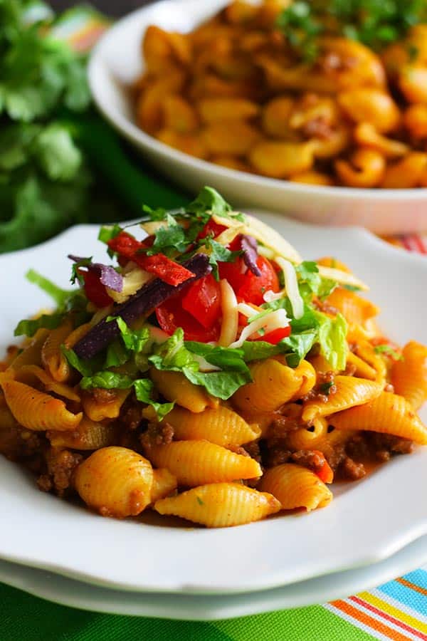a serving of this instant pot taco pasta garnished with cilantro and tomatoes in a white bowl