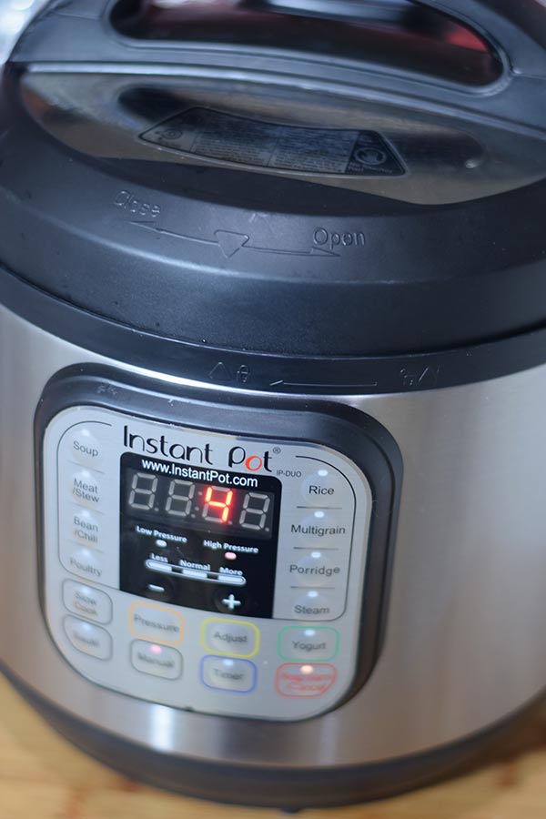 a closeup of the front of an instant pot set to cook on high pressure for four minutes