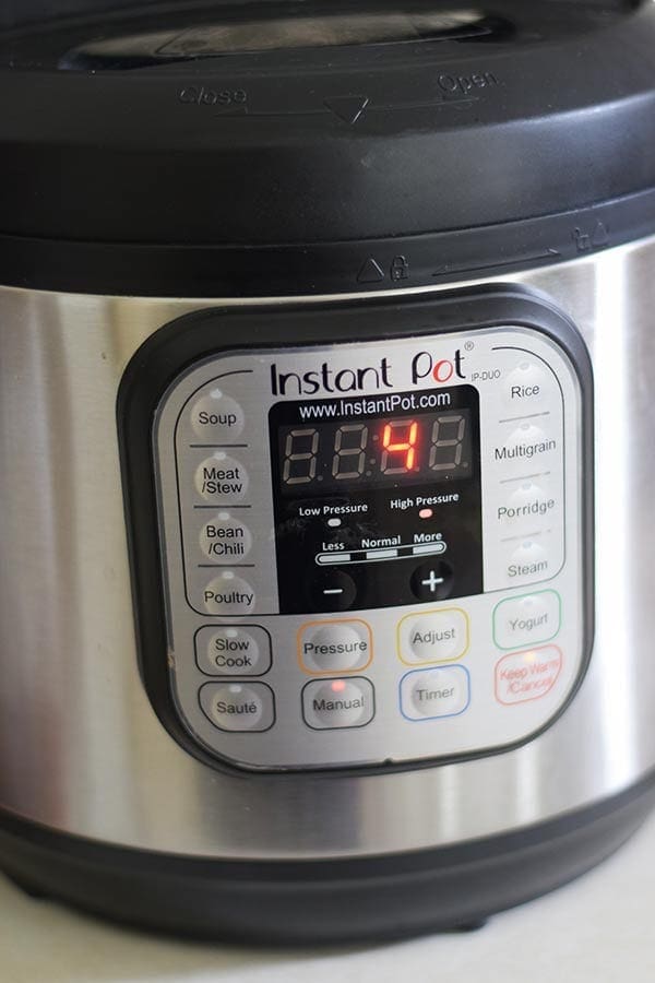a closeup of the face of an instant pot set to cook for four minutes on high to make this instant pot cheesy taco pasta