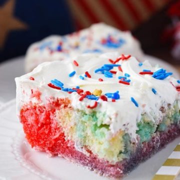 a slice of this red, white, and blue poke cake with whipped topping and colorful sprinkles