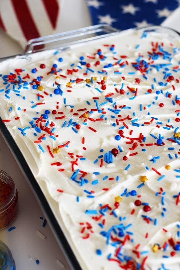 an overhead shot of this red, white, and blue poke cake with colorful fourth of july sprinkles
