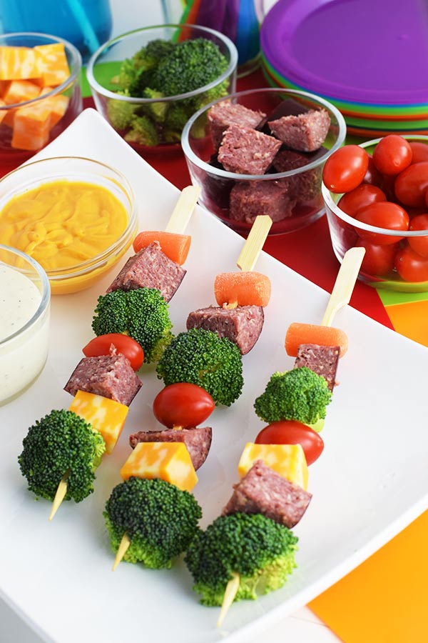 an overhead shot of these easy antipasto salami kebabs aka salami skewers with broccoli, cheese, carrots, and cherry tomatoes, mayonnaise and mustard on the side