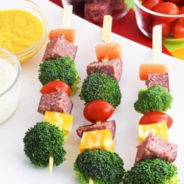 an overhead shot of these easy antipasto salami kebabs aka salami skewers with broccoli, cheese, carrots, and cherry tomatoes, mayonnaise and mustard on the side