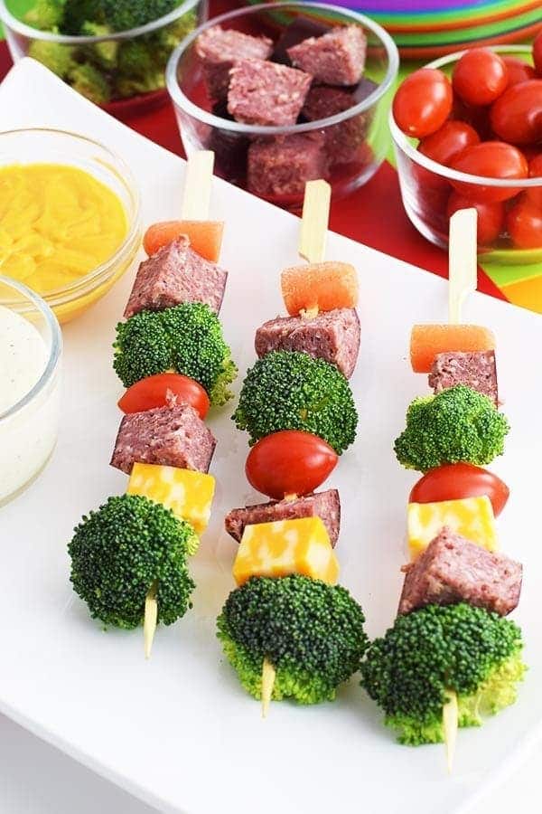 an overhead shot of these easy antipasto salami kebabs aka salami skewers with broccoli, cheese, carrots, and cherry tomatoes, mayonnaise and mustard on the side