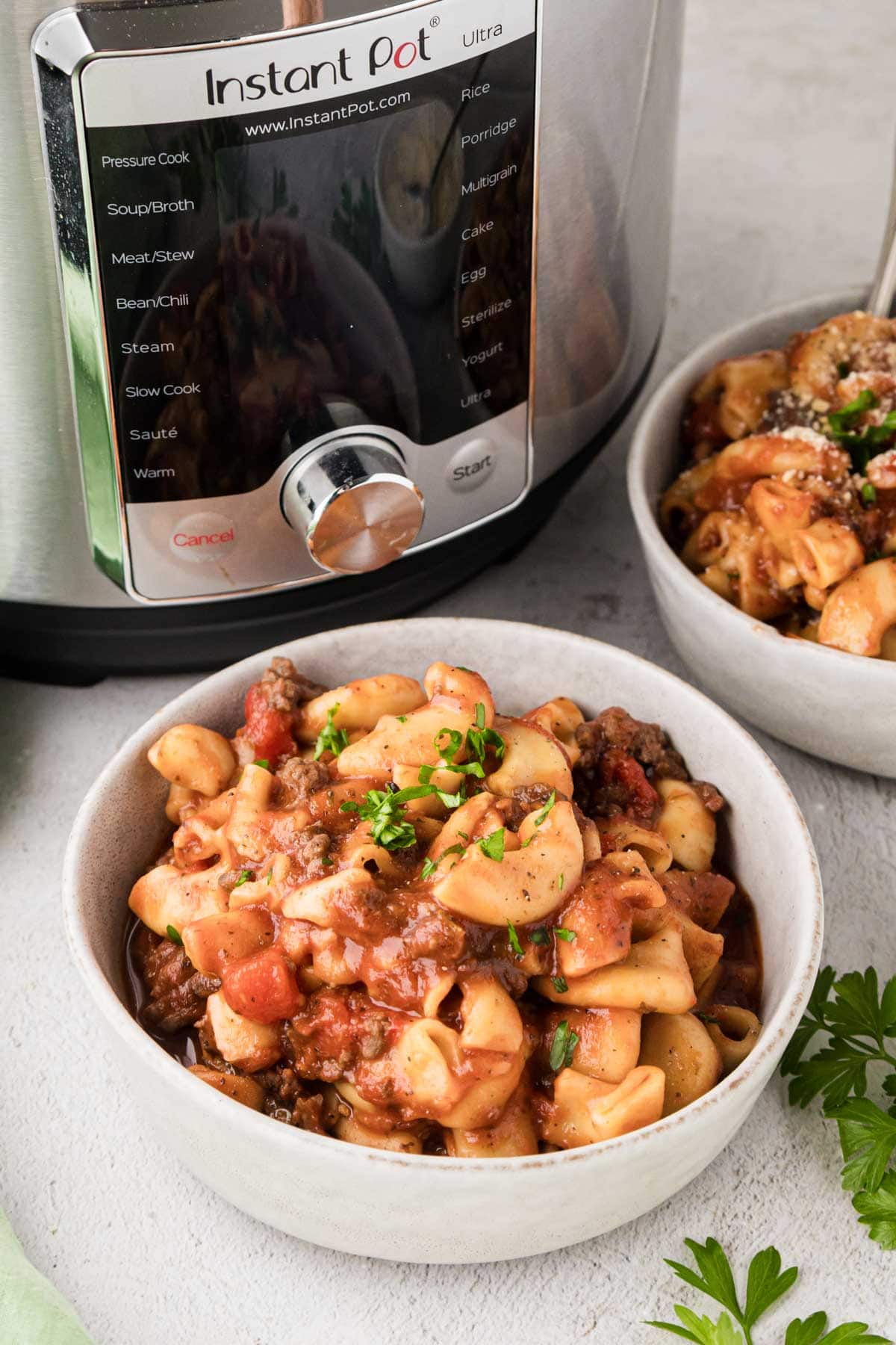 A bowl of instant pot American goulash garnished with parsley.