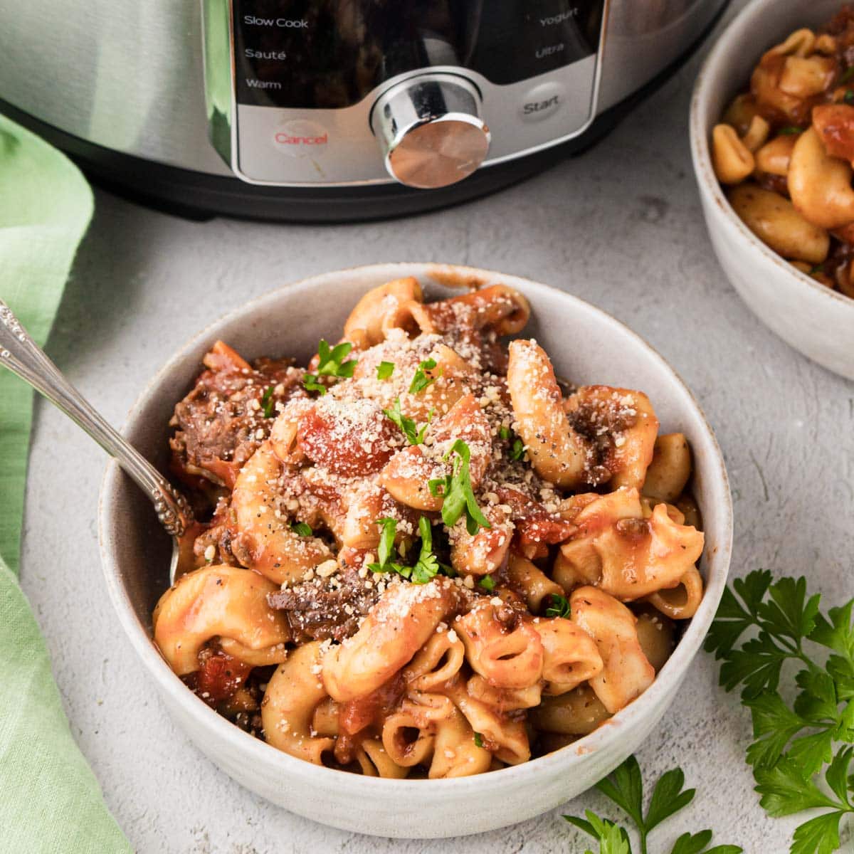 A bowl of instant pot American goulash garnished with parmesan cheese and parsley.