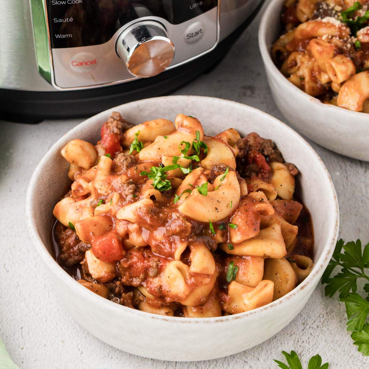 A bowl of instant pot American goulash garnished with parsley.