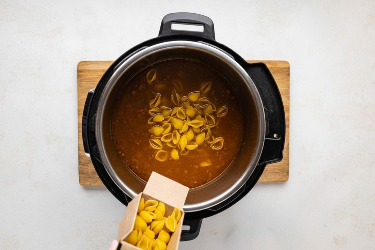 Shells pasta poured into the broth in the instant pot.