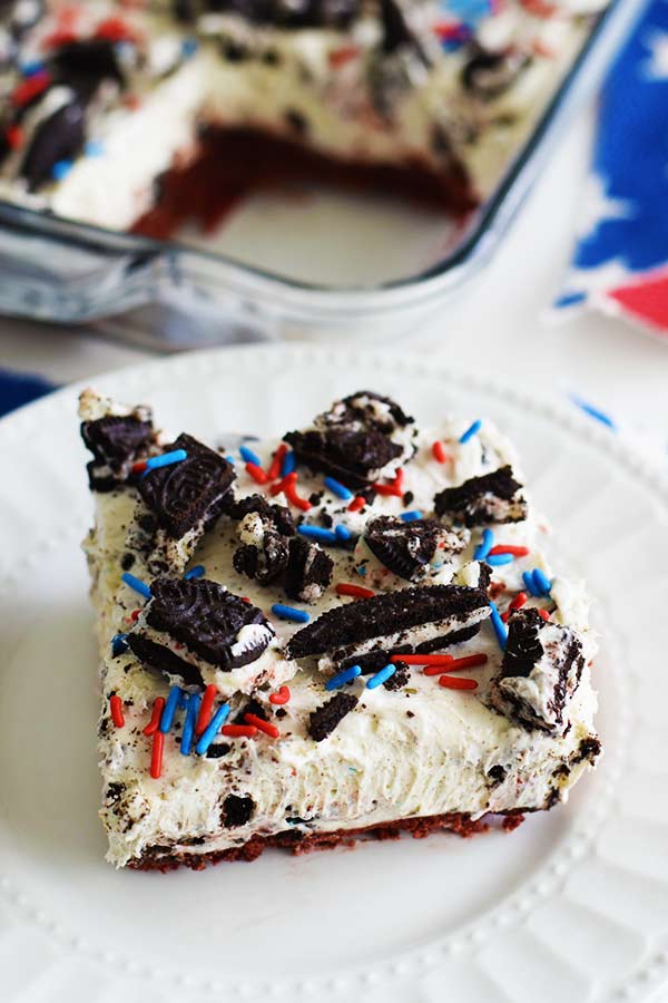 a slice of a no bake fireworks oreo cheesecake bar with red, white, and blue sprinkles and chopped oreos on top