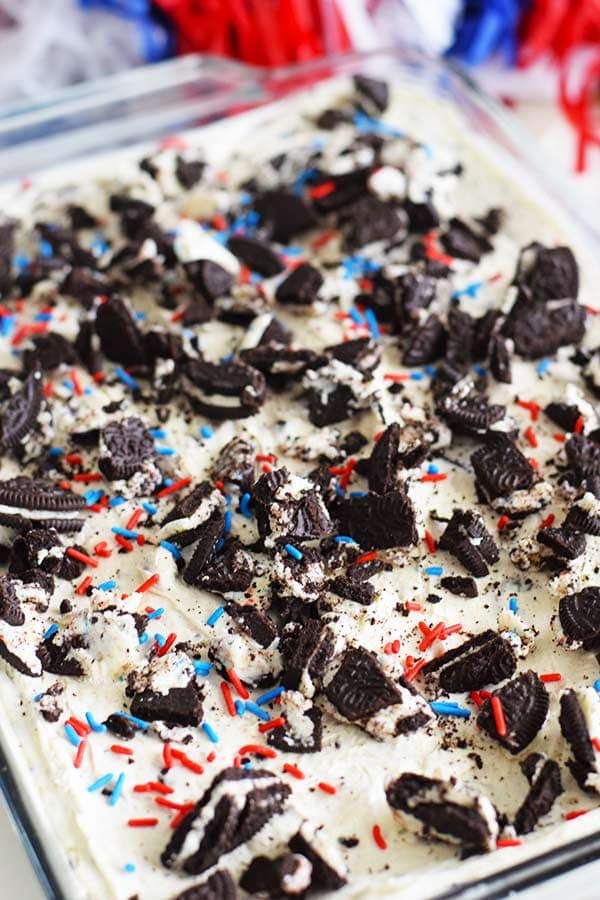 an overhead shot of these no bake fireworks oreo cheesecake bars with red, white, and blue sprinkles and chopped oreos on top