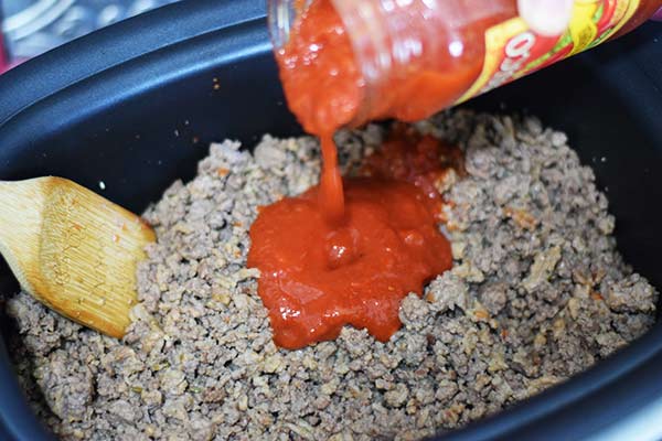 a closeup of ground beef in a crock pot with store-bought marinara sauce for this kicked up spaghetti sauce from a jar recipe