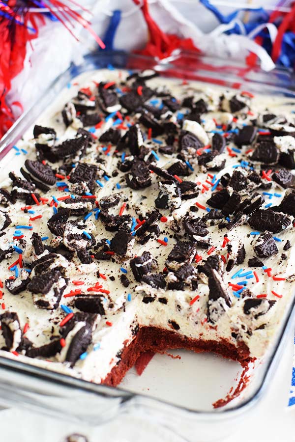 an overhead shot of these no bake fireworks oreo cheesecake bars with red, white, and blue sprinkles and chopped oreos on top with one slice missing