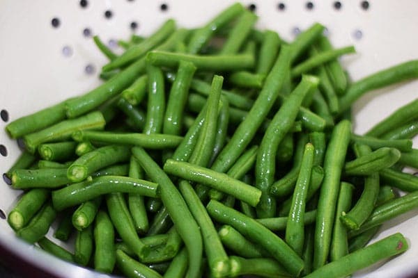A colander filled with freshly washed bright green green beans