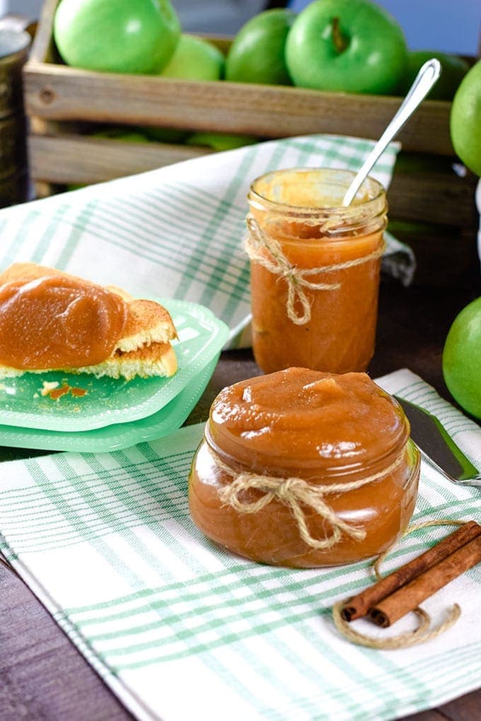 A picnic-style table with jars of this instant pot apple butter and slices of toast