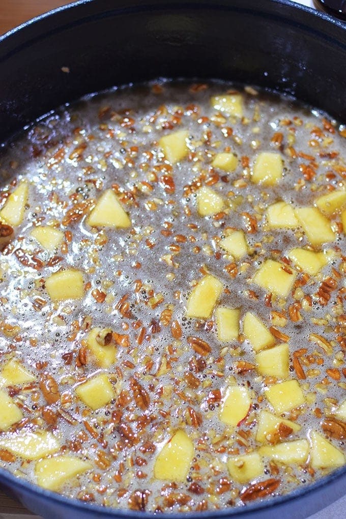 The bourbon pecan apple mixture in a cast iron skillet for this bourbon apple pecan bread pudding recipe