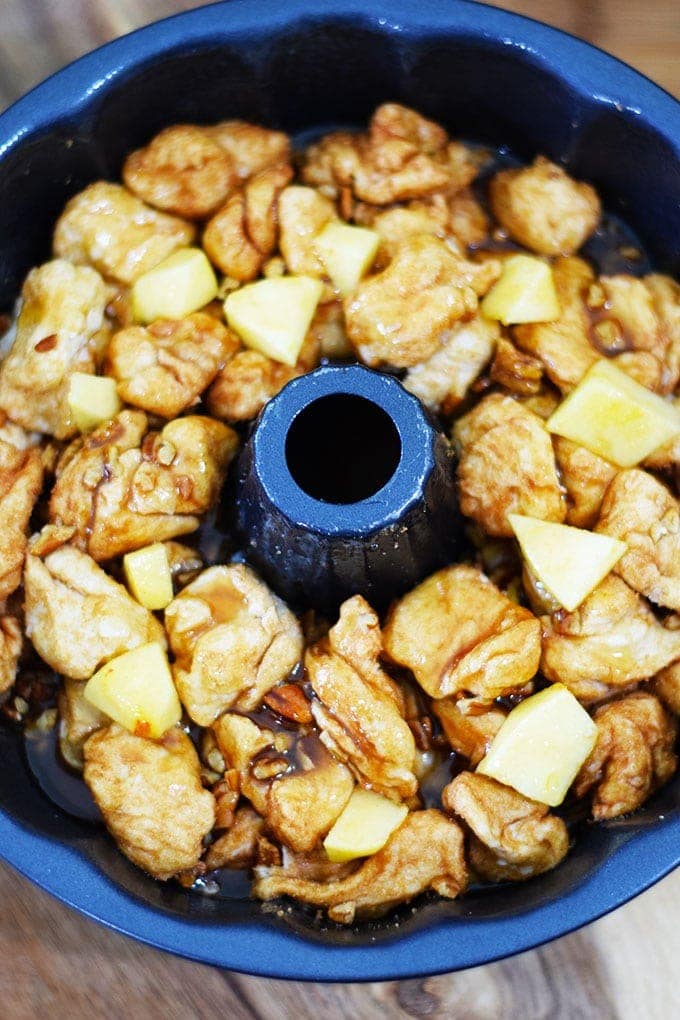 An overhead shot of the uncooked apple pecan sticky bun bites recipe with apple butter mixture and cinnamon sugar biscuit pieces