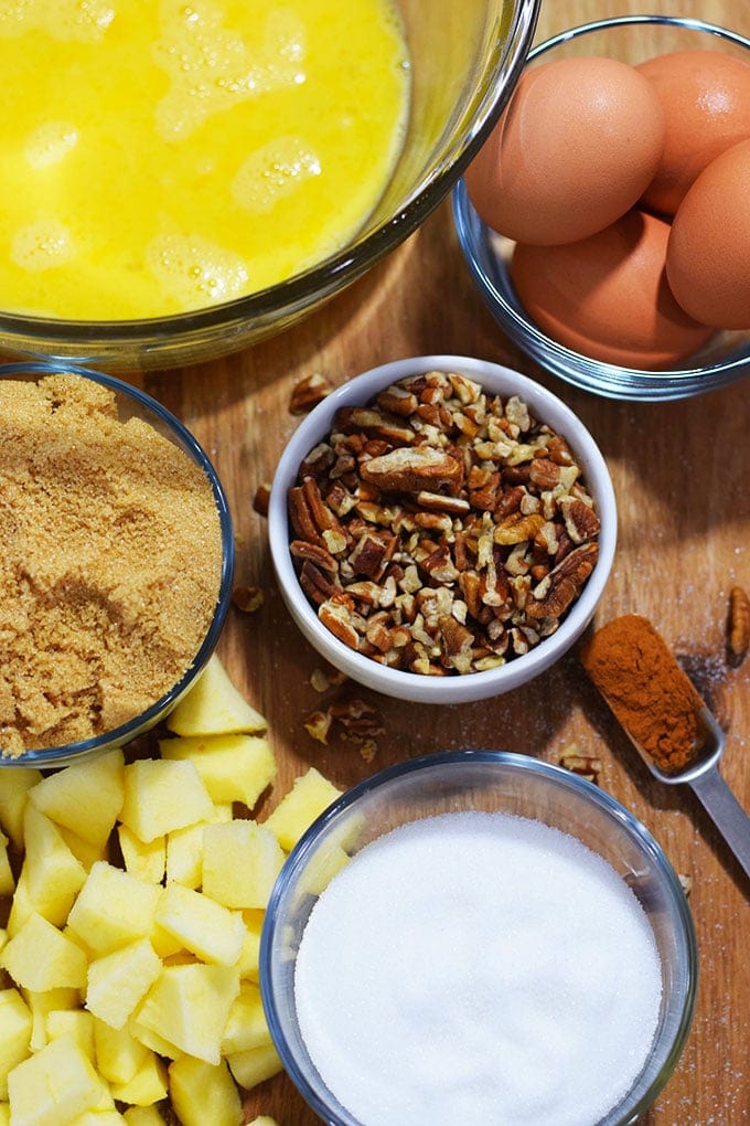 the ingredients for this bourbon apple pecan bread pudding recipe in an arrangement of bowls on a wooden cutting board