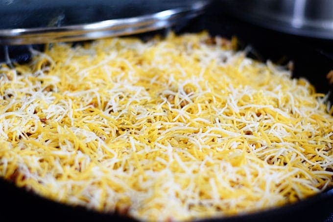 a closeup of the shredded cheese added to the top of this unstuffed pepper skillet
