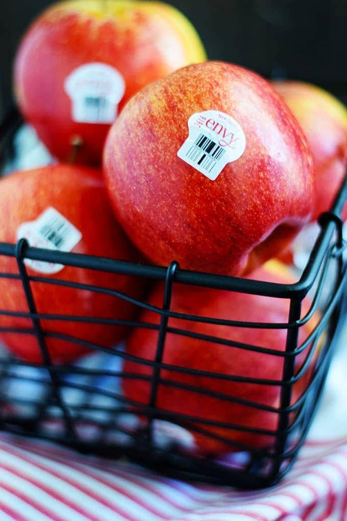 A close up of a basket of red envy apples