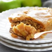 A closeup of this fresh apple cake with a brown sugar glaze on a white plate with a fork