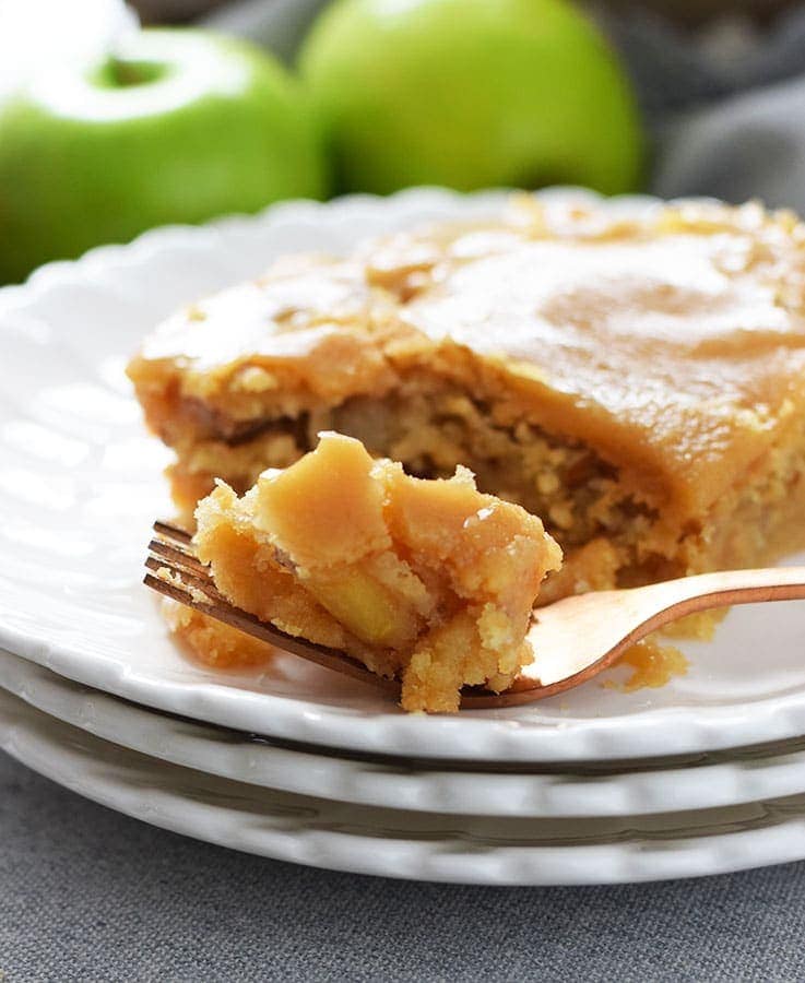 A closeup of this fresh apple cake with a brown sugar glaze on a white plate with a fork